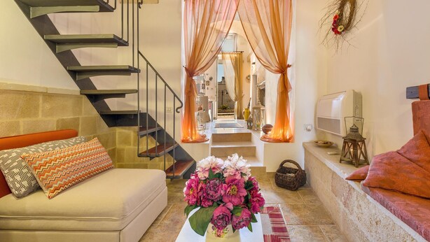 Un escalier au design moderne, un espace de vie avec un canapé et une table basse, et une guirlande décorative accrochée au mur.