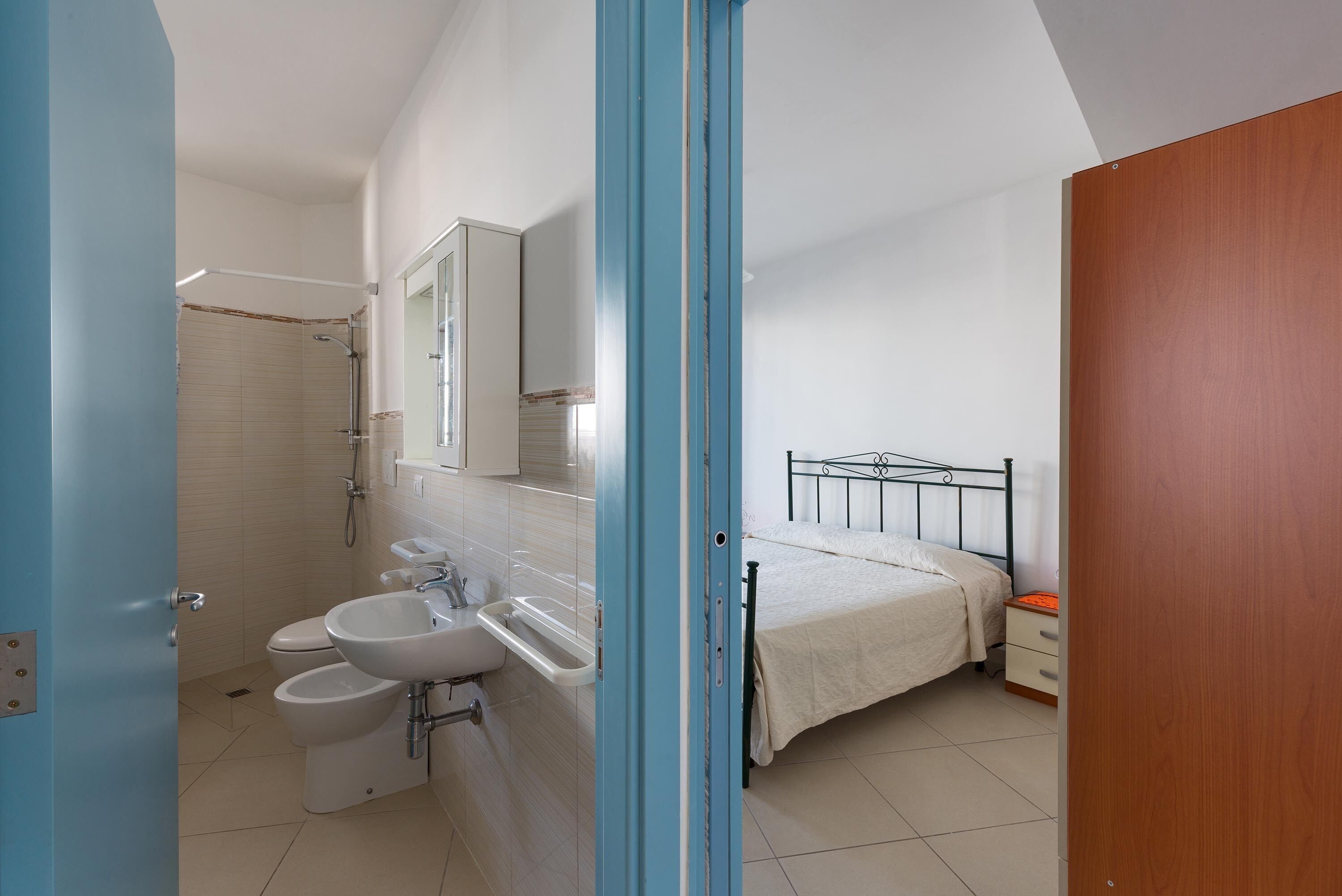A bedroom with a bed, bedside table, and a window.