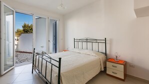 A bedroom with a bed, a nightstand, and a door leading to a balcony. - Villetta Catia (Nardò)