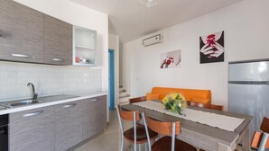 A modern kitchen with grey cabinets, a white countertop, and a stainless steel refrigerator. - Villetta Catia (Nardò)