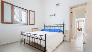 Ein Schlafzimmer mit einem Bett, einem Heizkörper, einem Spiegel und einer Tür zu einem anderen Raum.