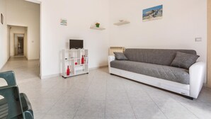 Ein modernes Wohnzimmer mit einem grauen Sofa, einem weißen Couchtisch und einer weißen Schrankwand mit Dekoration.