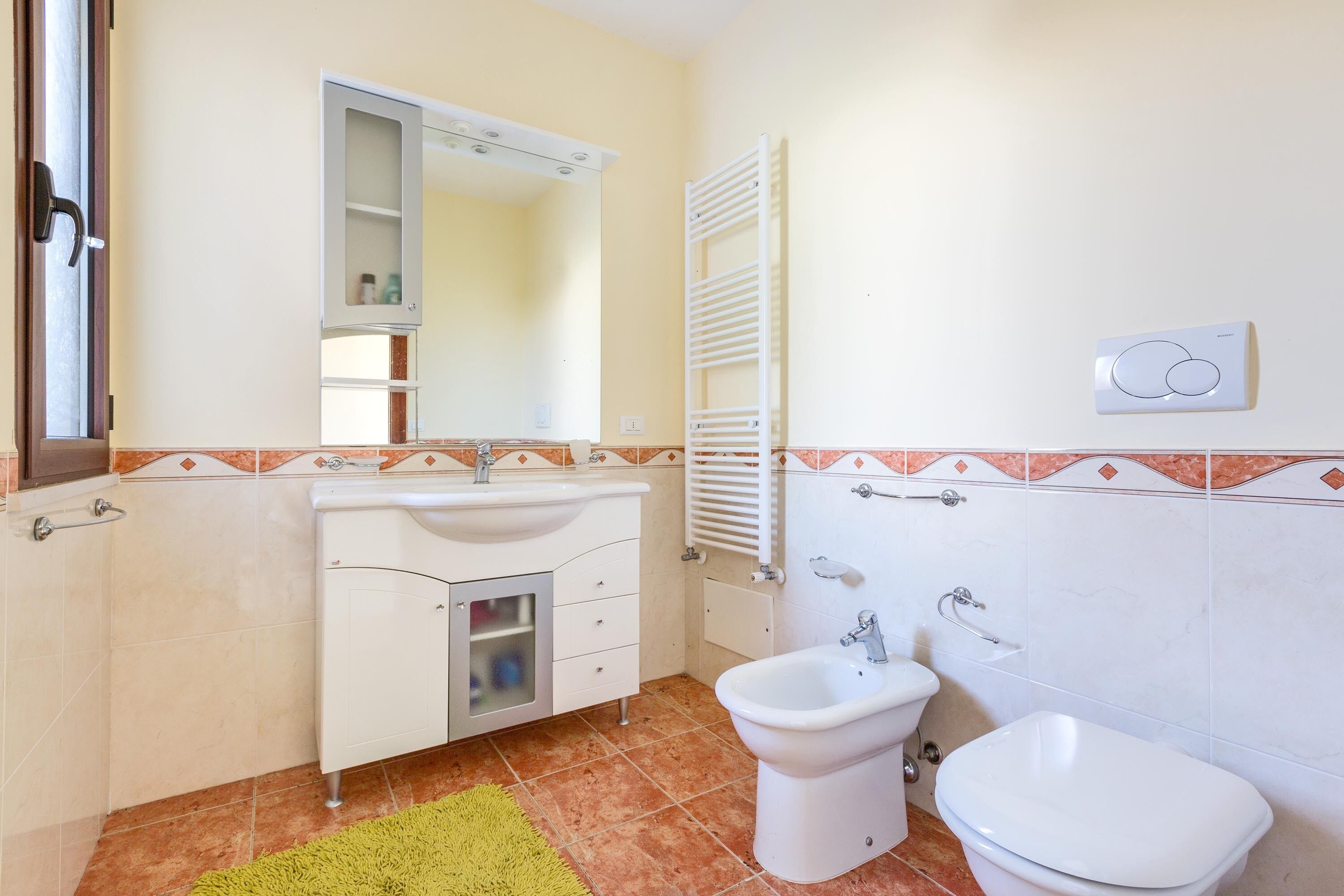 Un baño con lavamanos, bidé, inodoro, espejo y toallero.