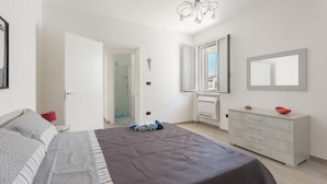 A bedroom with a bed, a dresser, a mirror, and a door leading to a bathroom.