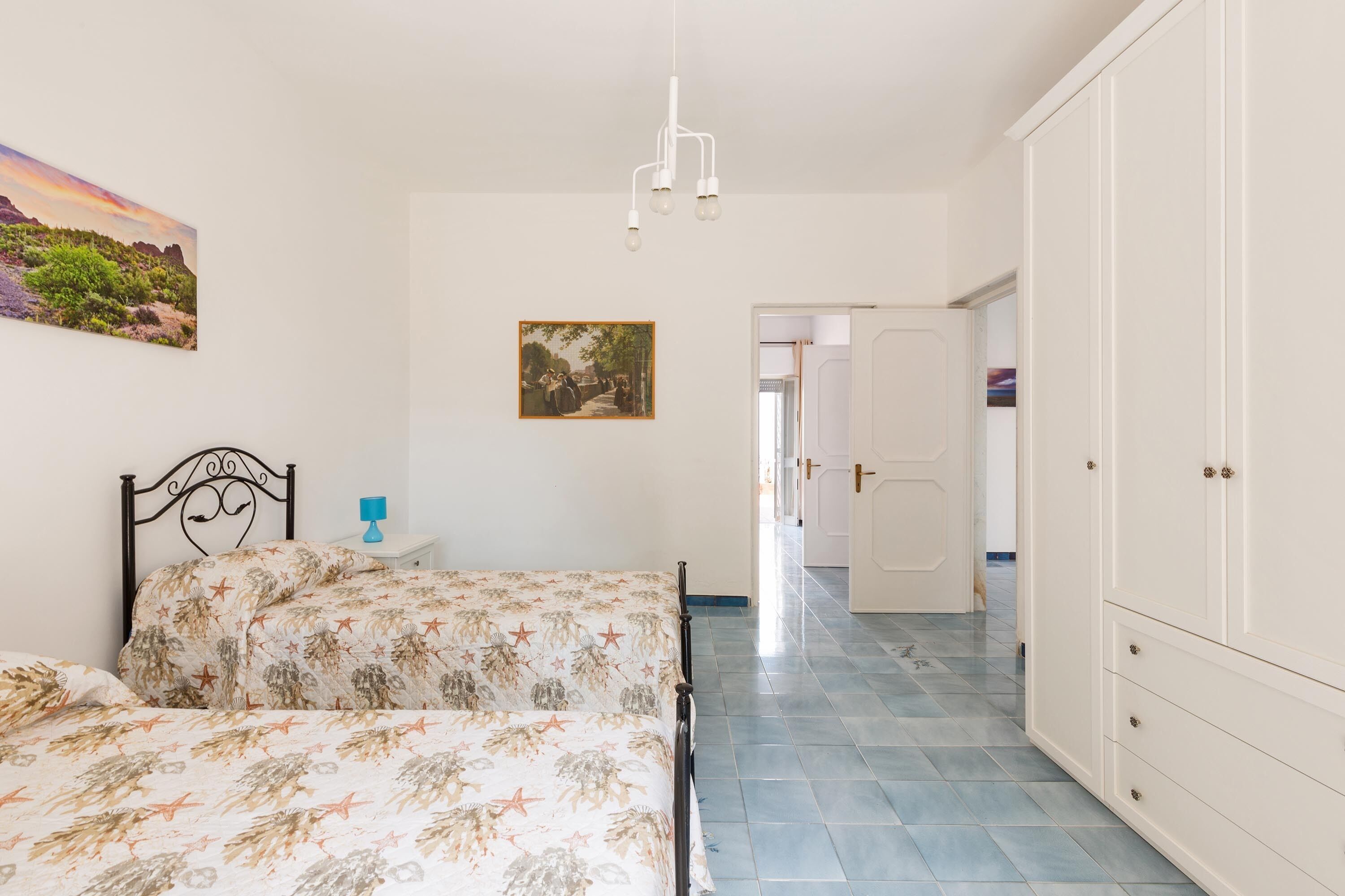 A bedroom with a bed, a nightstand, a wardrobe, and a painting on the wall.