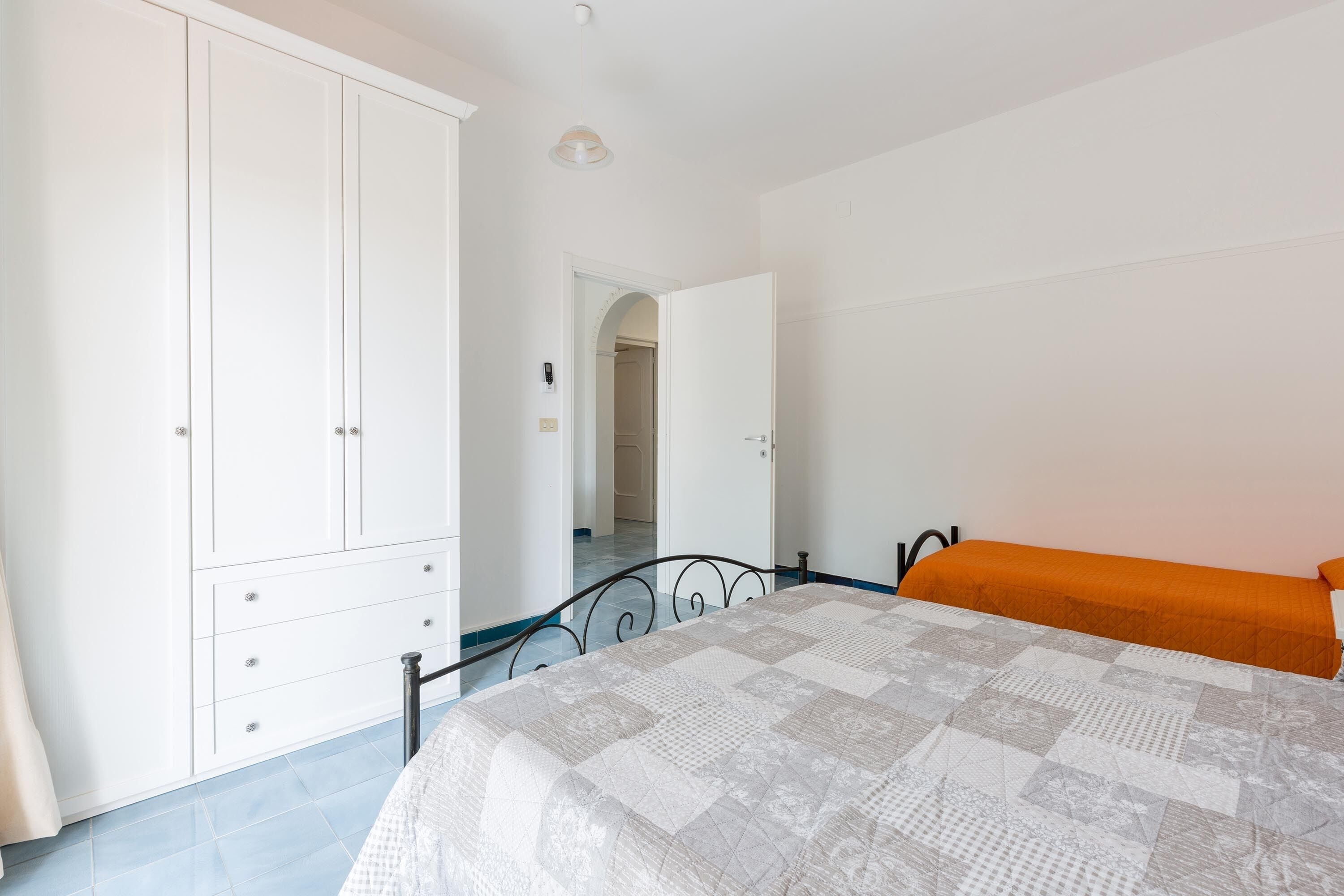Een slaapkamer met een bed, een kledingkast en een deur naar een andere kamer.