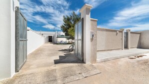 A clean, modern building entrance with a concrete pathway leading to a covered area. - Villa Melograno (Porto Cesareo)
