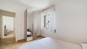 A bedroom with a large bed, a wardrobe, a mirror, and a window with curtains. - Villa Melograno (Porto Cesareo)