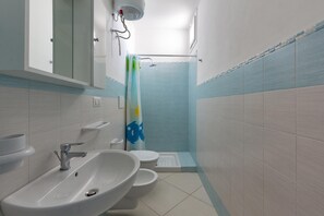 Un baño con lavamanos, inodoro y zona de ducha.