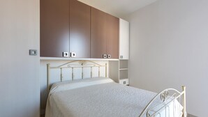 A bedroom with a bed, a wardrobe, and a shelf unit. - Villetta Raffaele (Nardò)