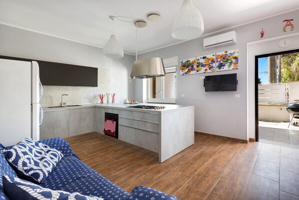 A modern kitchen with a central island, pendant lights, and a view to the outside.