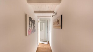 Un couloir doté d’un plancher en bois, de murs blancs et d’œuvres d’art.