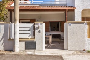 A residential property with a covered patio, a wooden table, and a chair.