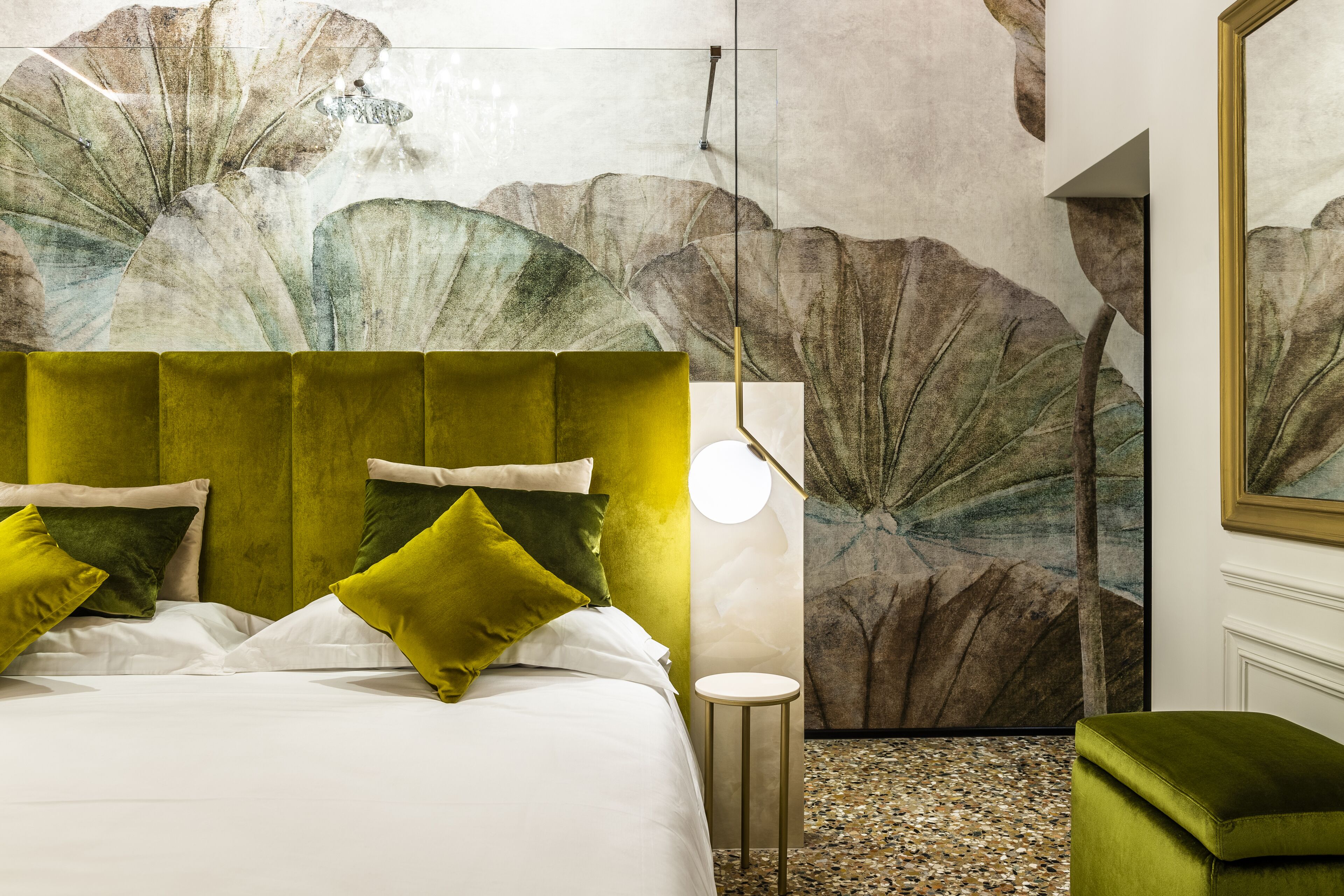 A modern bedroom with a green upholstered headboard, white bedding, and a large floral mural on the wall.
