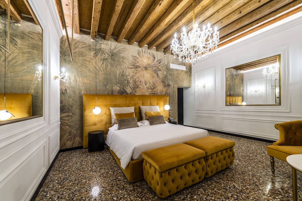 Une chambre à coucher avec un grand lit, un lustre et un miroir.