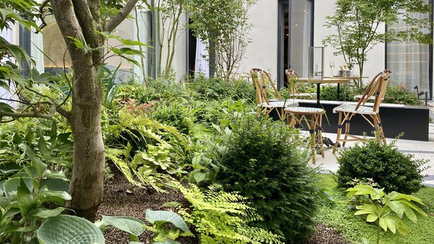 An outdoor seating area with tables and chairs, surrounded by various plants and trees. - Maison Albar Hotels Le Vendome (Paris)