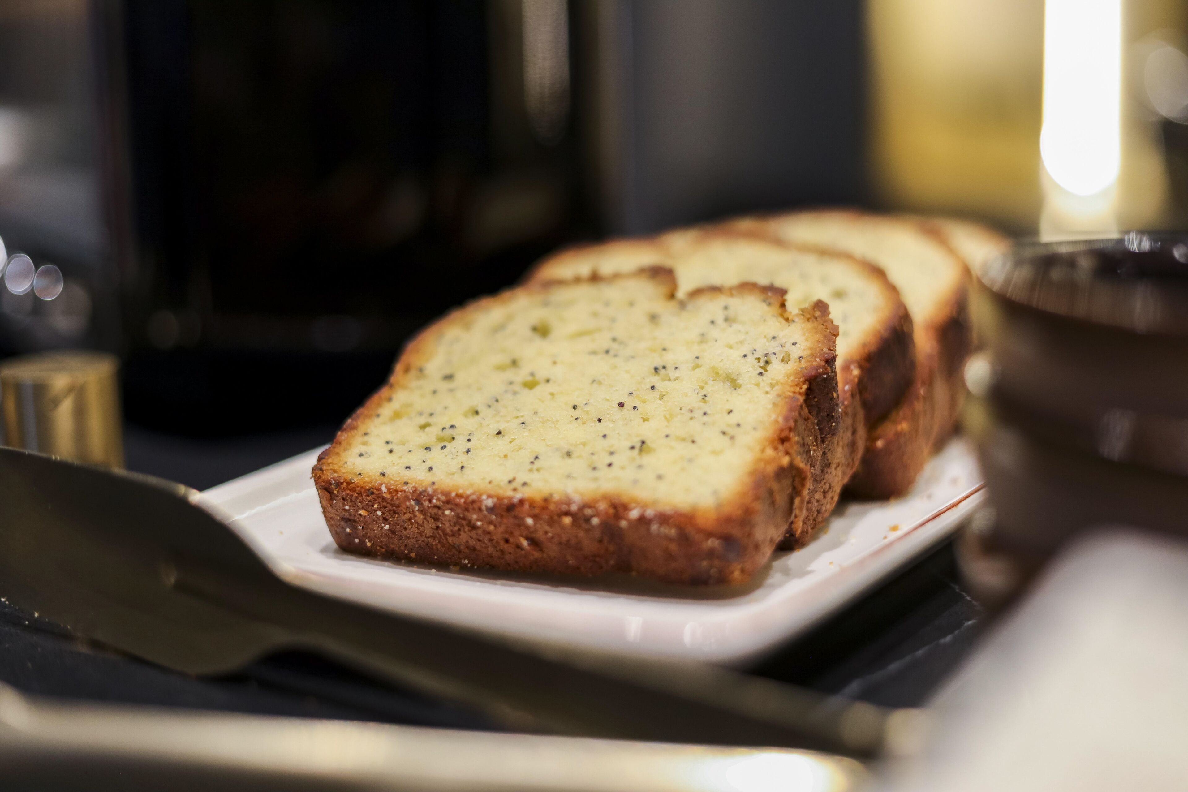 A slice of bread on a white plate with a knife beside it.