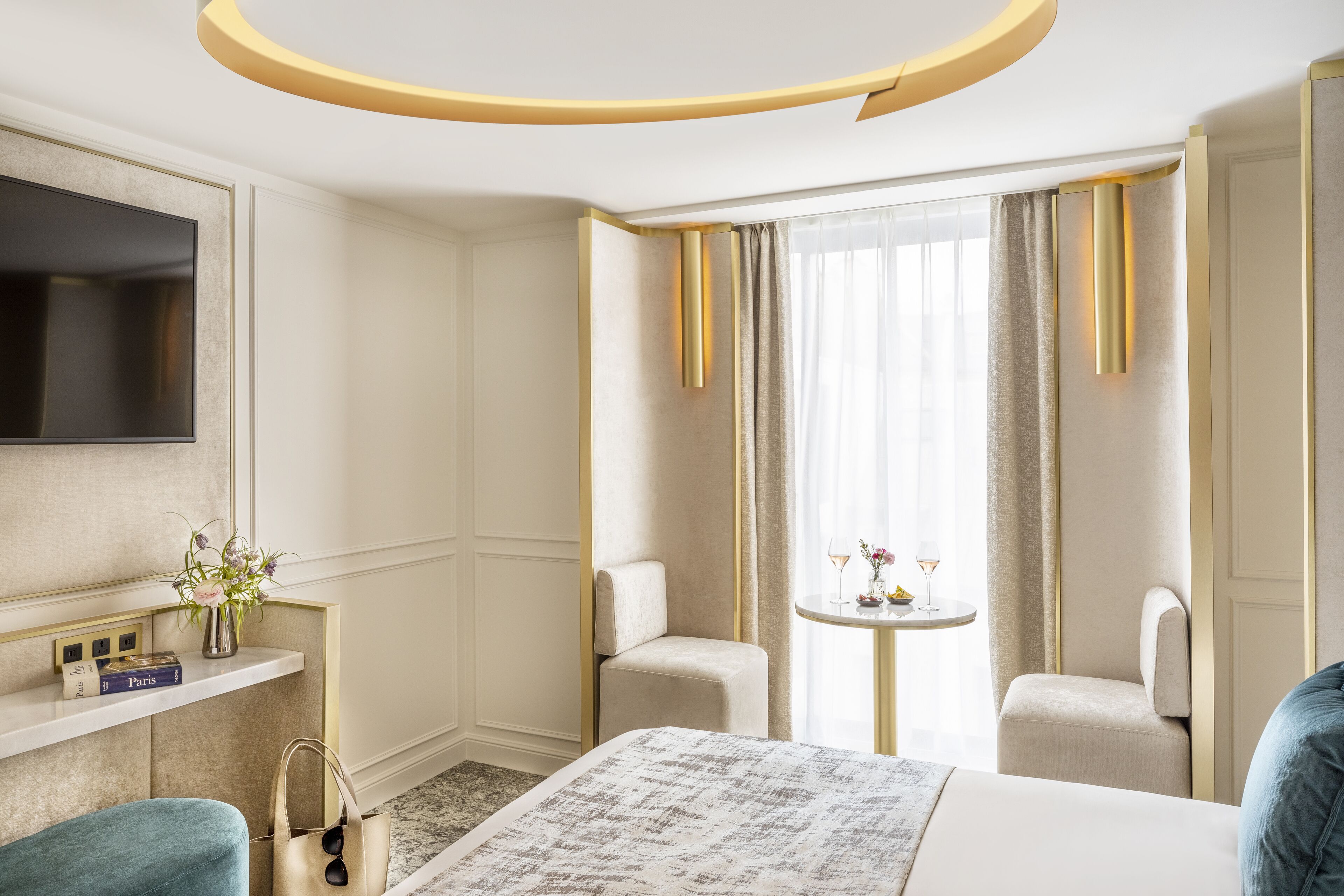 A hotel room with a bed, a TV, a small table with drinks, and two chairs.