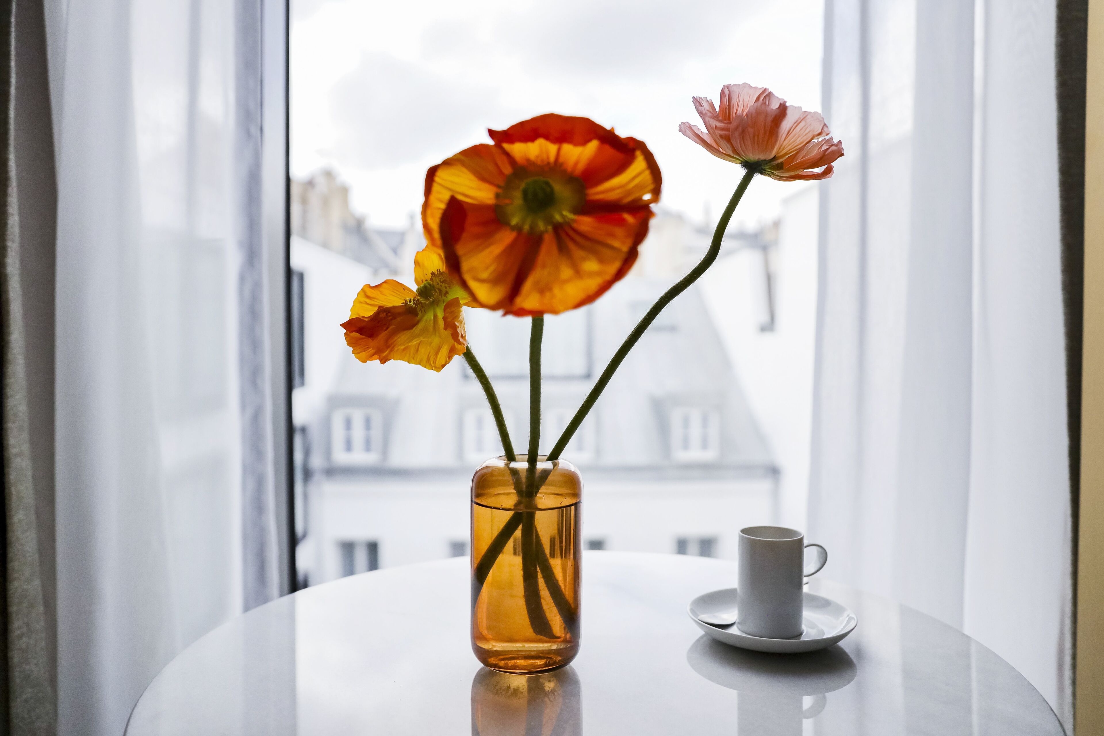 A vase with flowers on a table by a window.