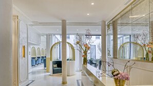 A modern hotel lobby with a reception desk, seating area, and large windows. - Maison Albar Hotels Le Vendome (Paris)
