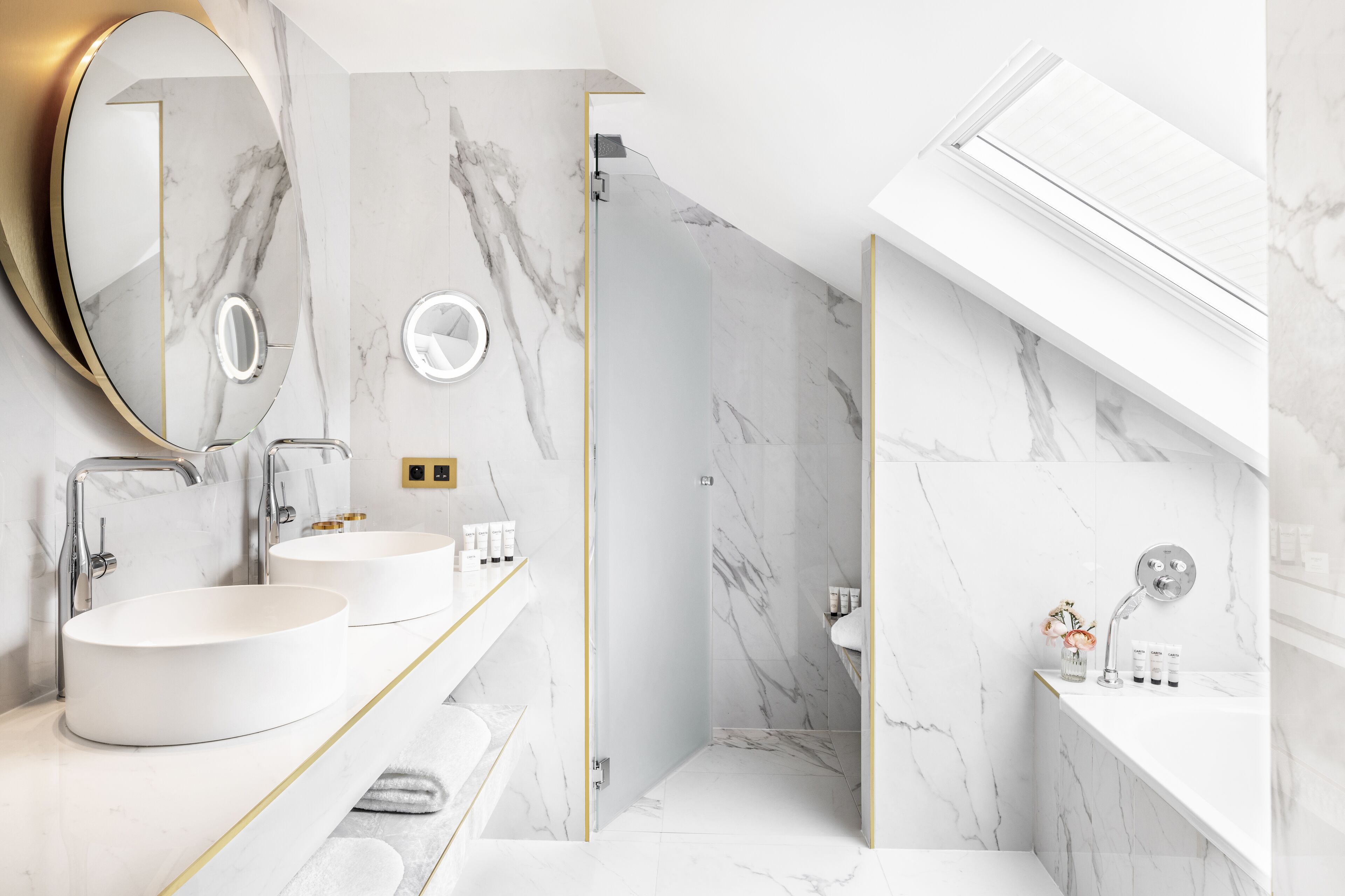 A modern bathroom with two round sinks, a walk-in shower, and a large mirror.