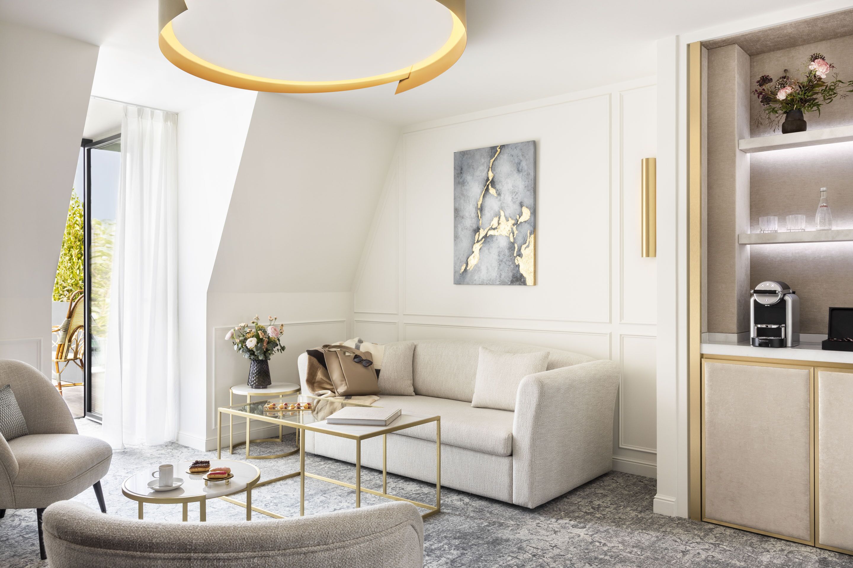 Ein modernes Wohnzimmer mit einer Couch, einem Couchtisch und Sesseln. Ein Bücherregal mit Dekoration und ein Bild an der Wand.