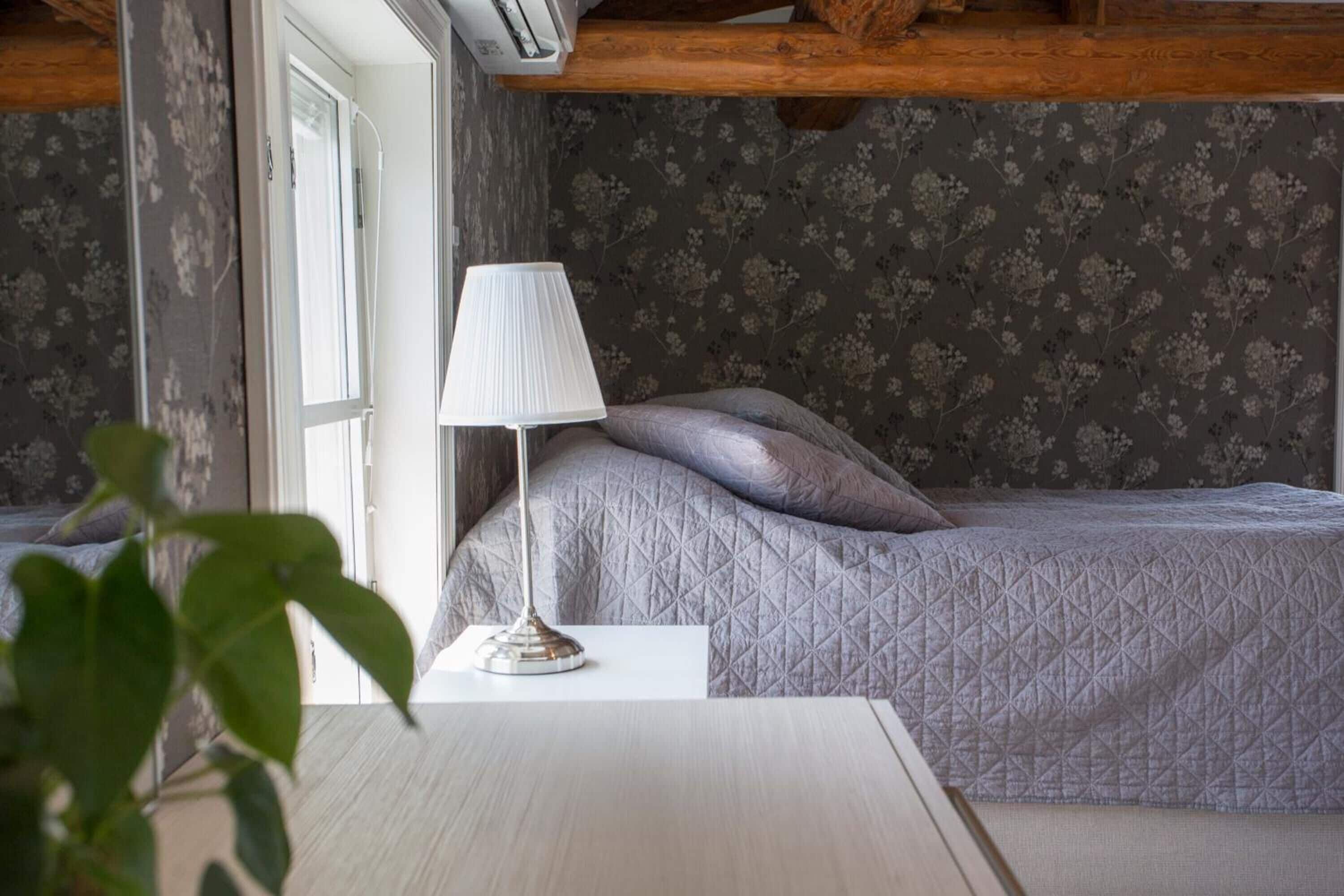 Une chambre à coucher avec un lit, une lampe de chevet et une fenêtre.