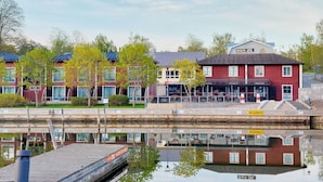 Et hotel ved vandet med flere bygninger, en bro og et spejlbillede i vandet.