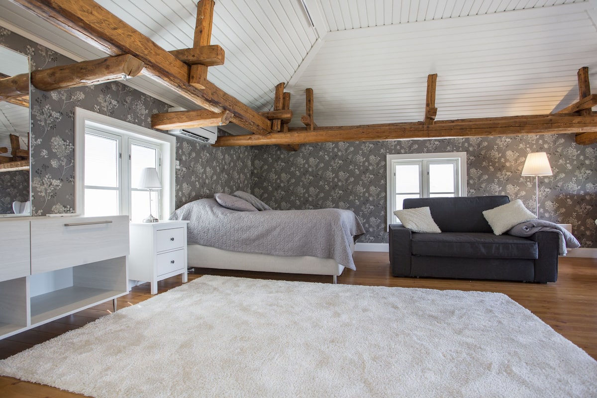 Ein Schlafzimmer mit einem großen Bett, einem Schlafsofa, einem Schminktisch und einem Spiegel.