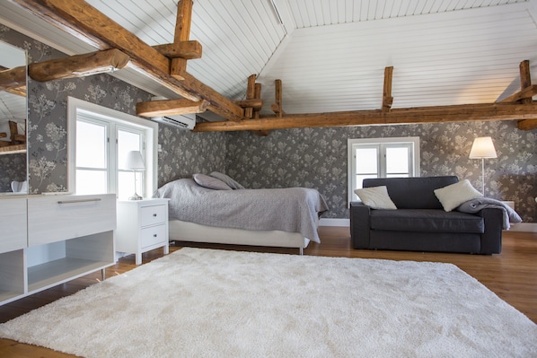 Un dormitorio con una cama grande, un sofá, un aparador y un espejo.