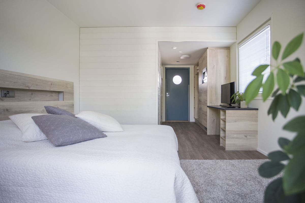 Ein modernes Schlafzimmer mit einem großen Bett, einem Schreibtisch und einem Fernseher.