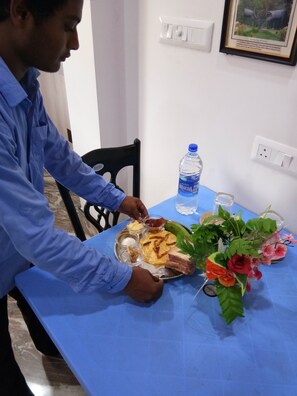 A dining table with a blue tablecloth, a plate of food, a water bottle, and a framed picture on the wall.