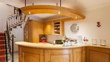 Una cocina con armarios de madera, techo de madera curvada, un reloj en la pared y una escalera con peldaños rojos.
