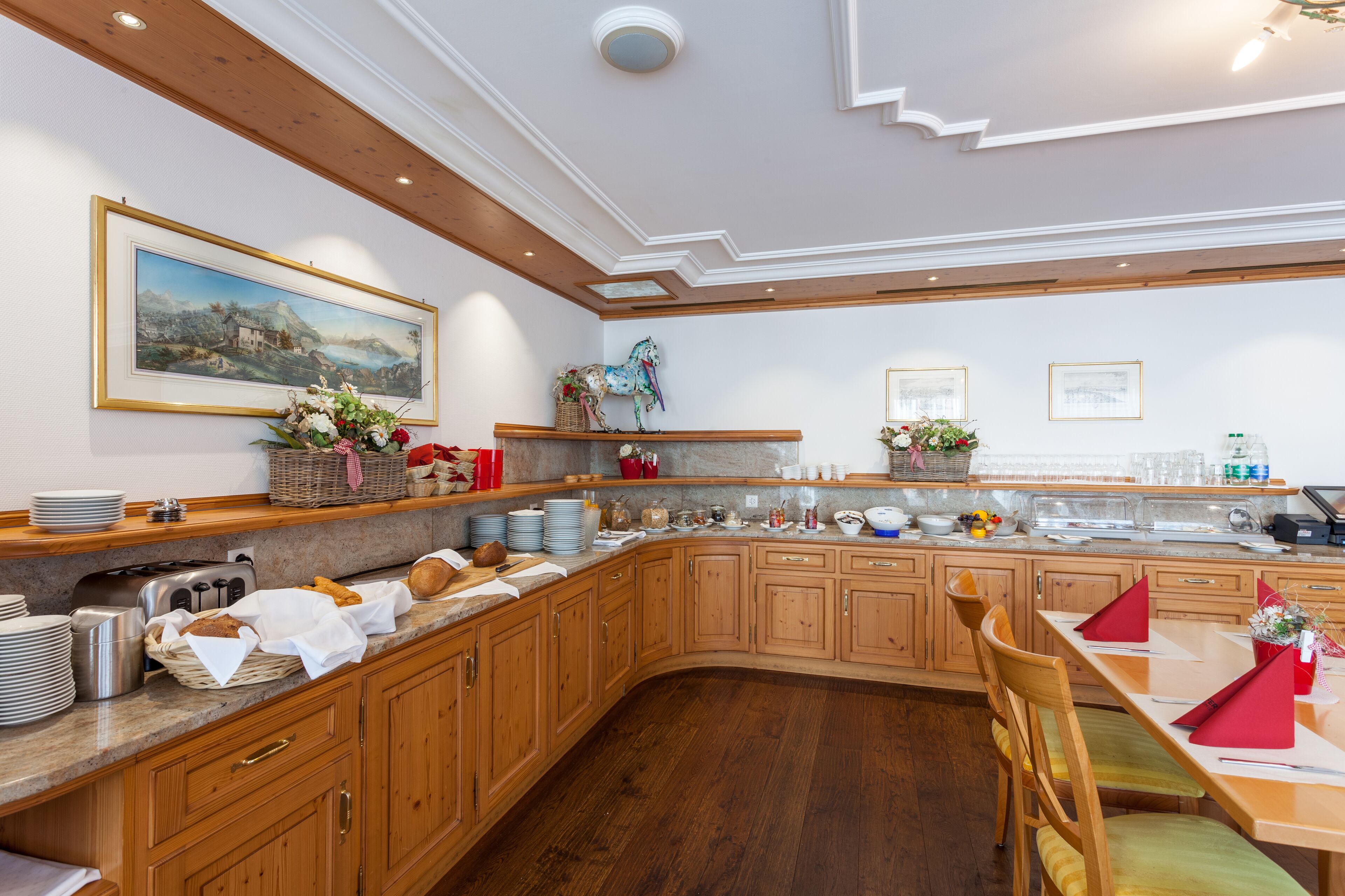 Een ruime keuken met houten kastjes, een marmeren aanrechtblad en een eethoek met een houten tafel en stoelen.
