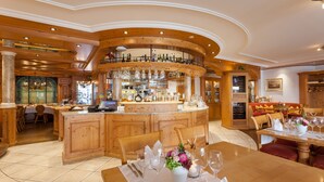 A spacious, elegantly designed restaurant with a central bar, wooden furniture, and a cozy seating area. - Weisses Rössli Swiss Quality Hotel (Ingenbohl)