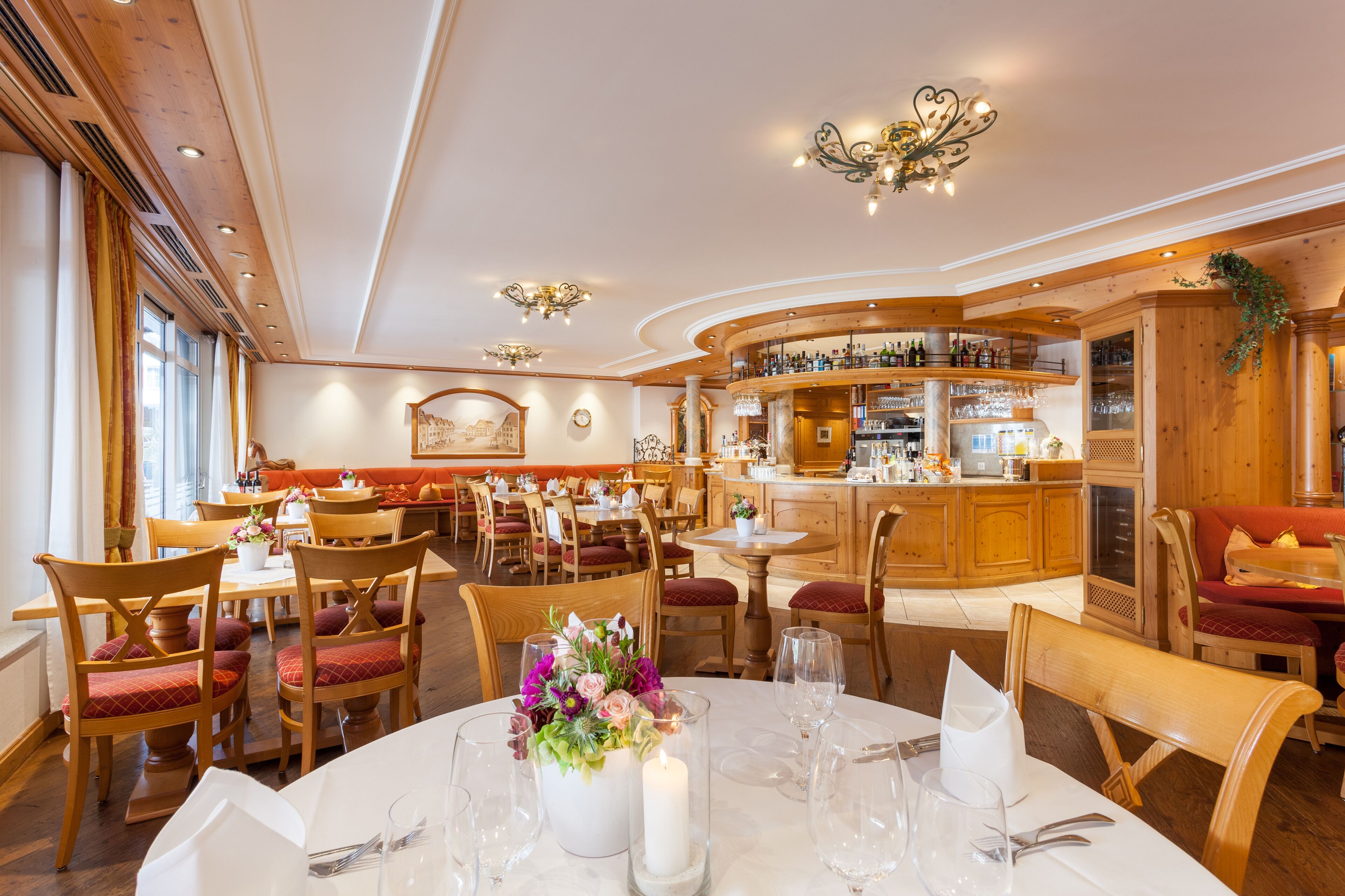 A restaurant with wooden interiors, a bar area, and dining tables set for guests.