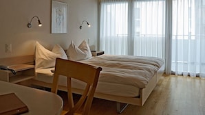 A bedroom with a bed, bedside tables, a chair, and a desk. - Weisses Rössli Swiss Quality Hotel (Ingenbohl)