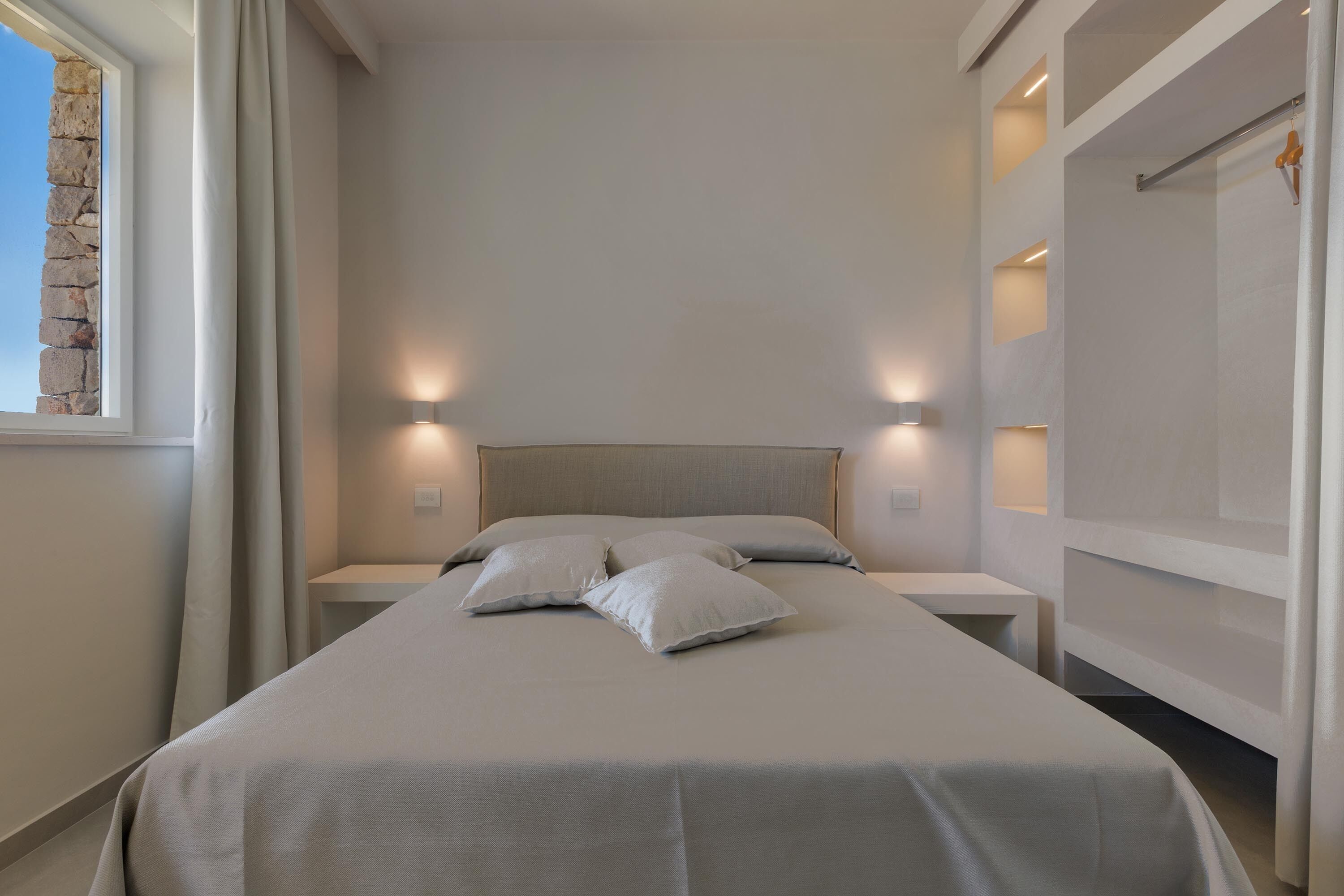A modern bedroom with a large bed, two bedside tables, and a headboard.