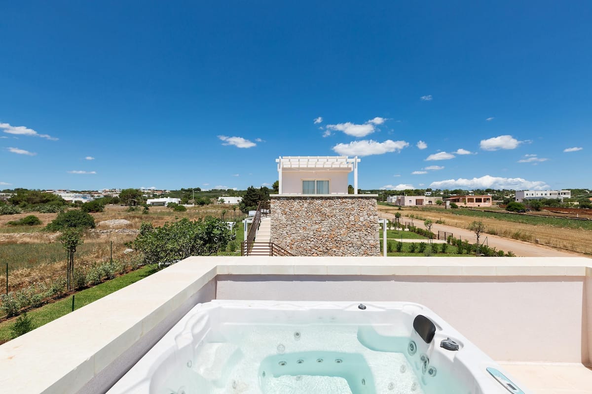 Ein Whirlpool auf einem Balkon mit Blick auf eine Steinsäule und einen wolkenlosen, blauen Himmel.