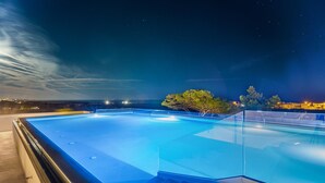 A rectangular swimming pool with clear blue water, surrounded by glass railings, set against a night sky with visible stars. - Perla Saracena Luxury Suites (Salve)