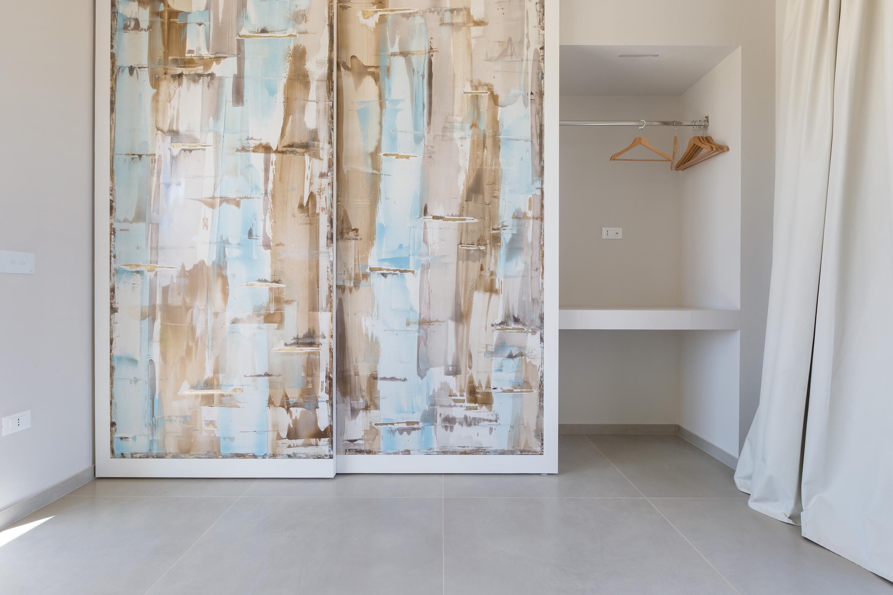 A room with a sliding door, a wooden hanger, and a white shelf.