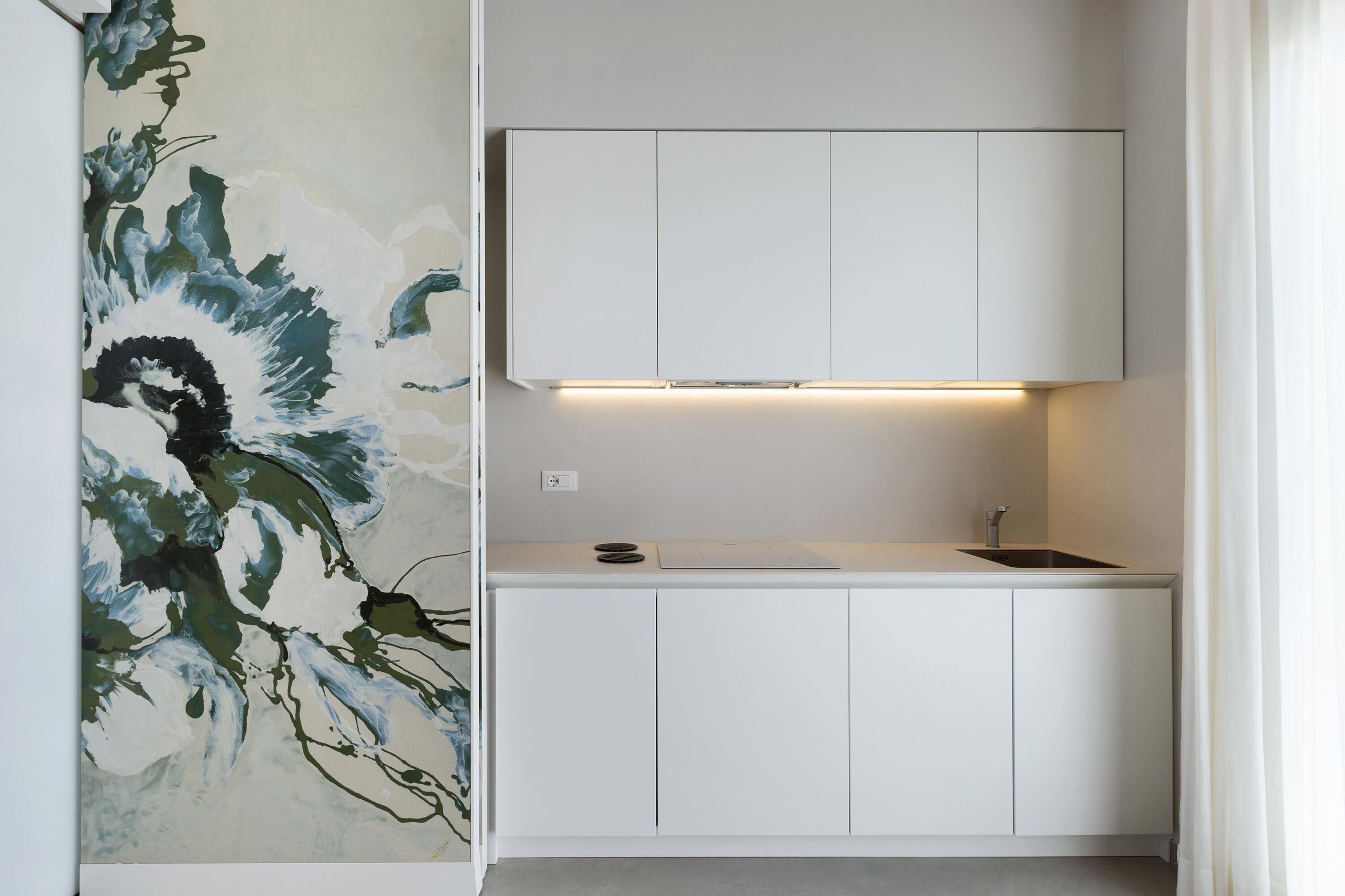 A modern kitchen with white cabinetry, a built-in sink, and under-cabinet lighting.