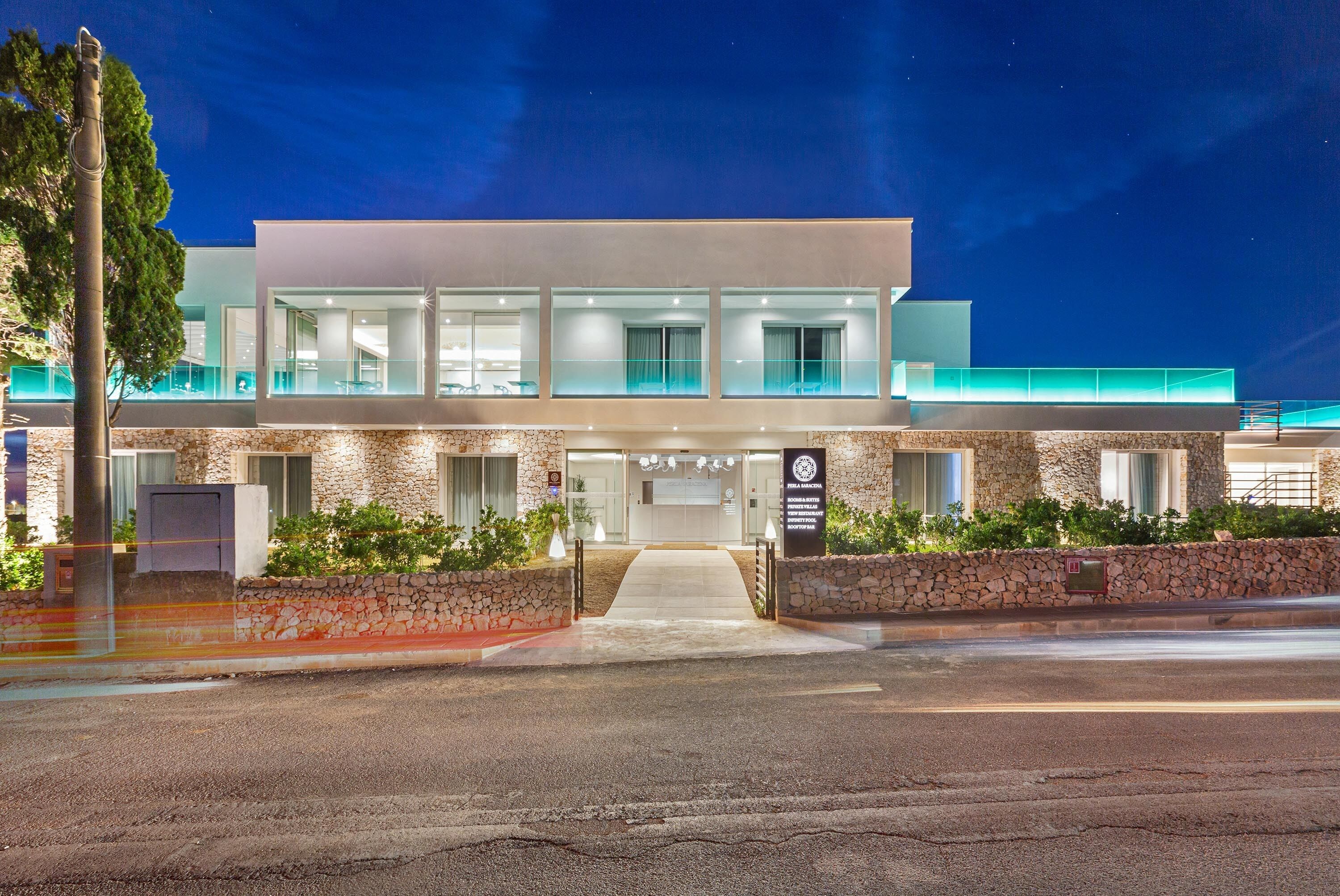 Un hotel moderno con fachada de piedra, ventanas amplias y una entrada bien iluminada.