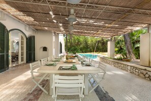 A covered outdoor dining area with a pool in the background. - Villa Denise (Castellaneta)