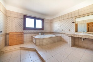 Un baño con bañera, tocador con espejo y ventana.