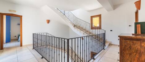 A spacious room with a curved staircase, a wooden cabinet, and a view of the outside.