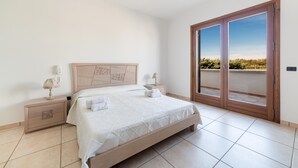 Un dormitorio con cama, mesitas de noche y puerta corrediza al exterior.