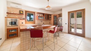 Una cocina moderna con una isla central, electrodomésticos de acero inoxidable y taburetes rojos.