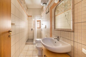 A narrow bathroom with a sink, toilet, and shower. - Villetta Specchiarica (Manduria)