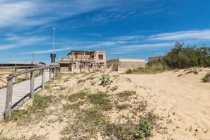 A sandy beach with a wooden boardwalk leading to a building with a balcony. - Villetta Specchiarica (Manduria)